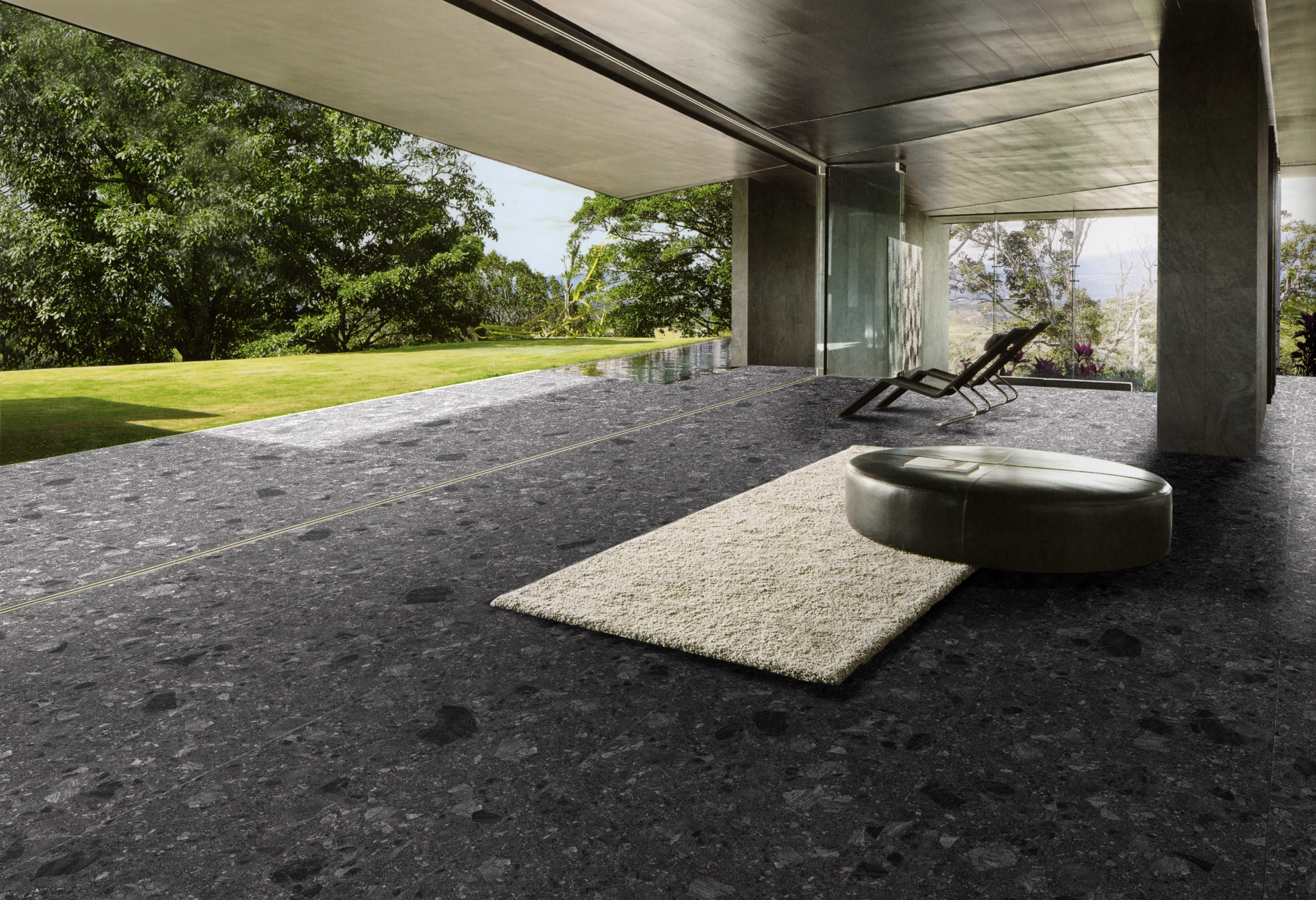 Luxurious open-concept space with dark terrazzo-look porcelain tiles, a minimalist lounge chair, a plush area rug, and a seamless indoor-outdoor transition.