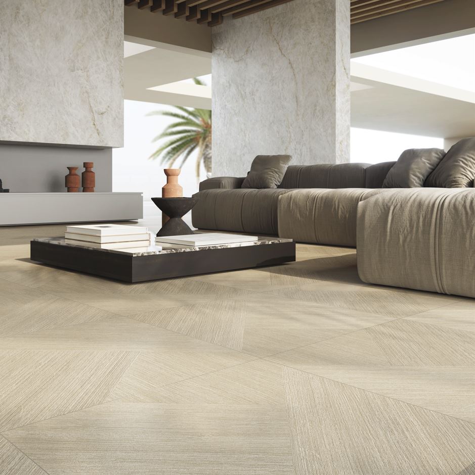 Modern living room with beige wood-look porcelain tiles, a low black coffee table, a large gray sectional sofa, and an open-concept design with natural light.