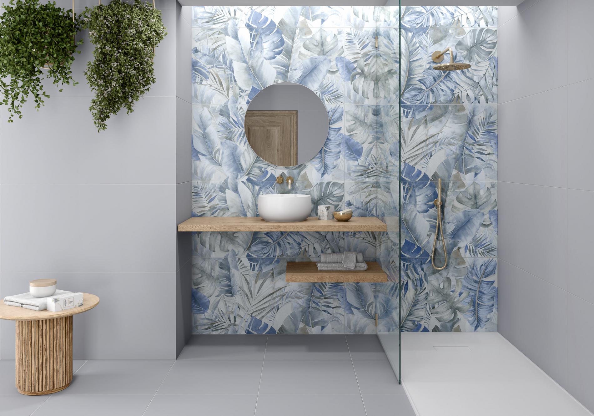 Modern bathroom with blue and white floral-patterned porcelain tiles, a floating wooden vanity, round mirror, and a glass-enclosed shower area.